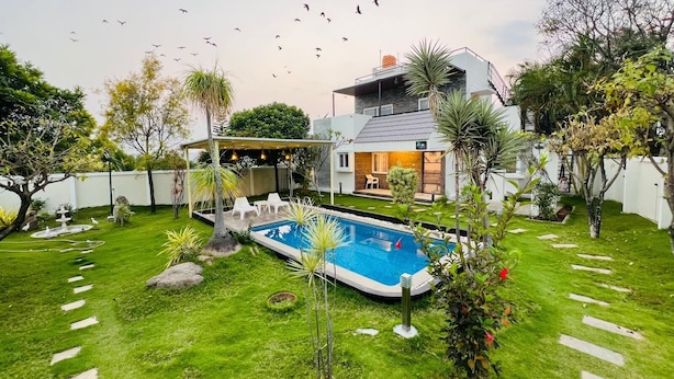 Ein Wohnhaus mit Schwimmbad, Terrassenmöbeln und einer überdachten Außenbereich.