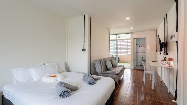A modern hotel room with a large bed, a sofa, a desk, and a view of the outside. - Cool Cozy 3-bedroom townhome in Chinatown Krung Thep Maha Nakhon (Krung Thep Maha Nakhon)