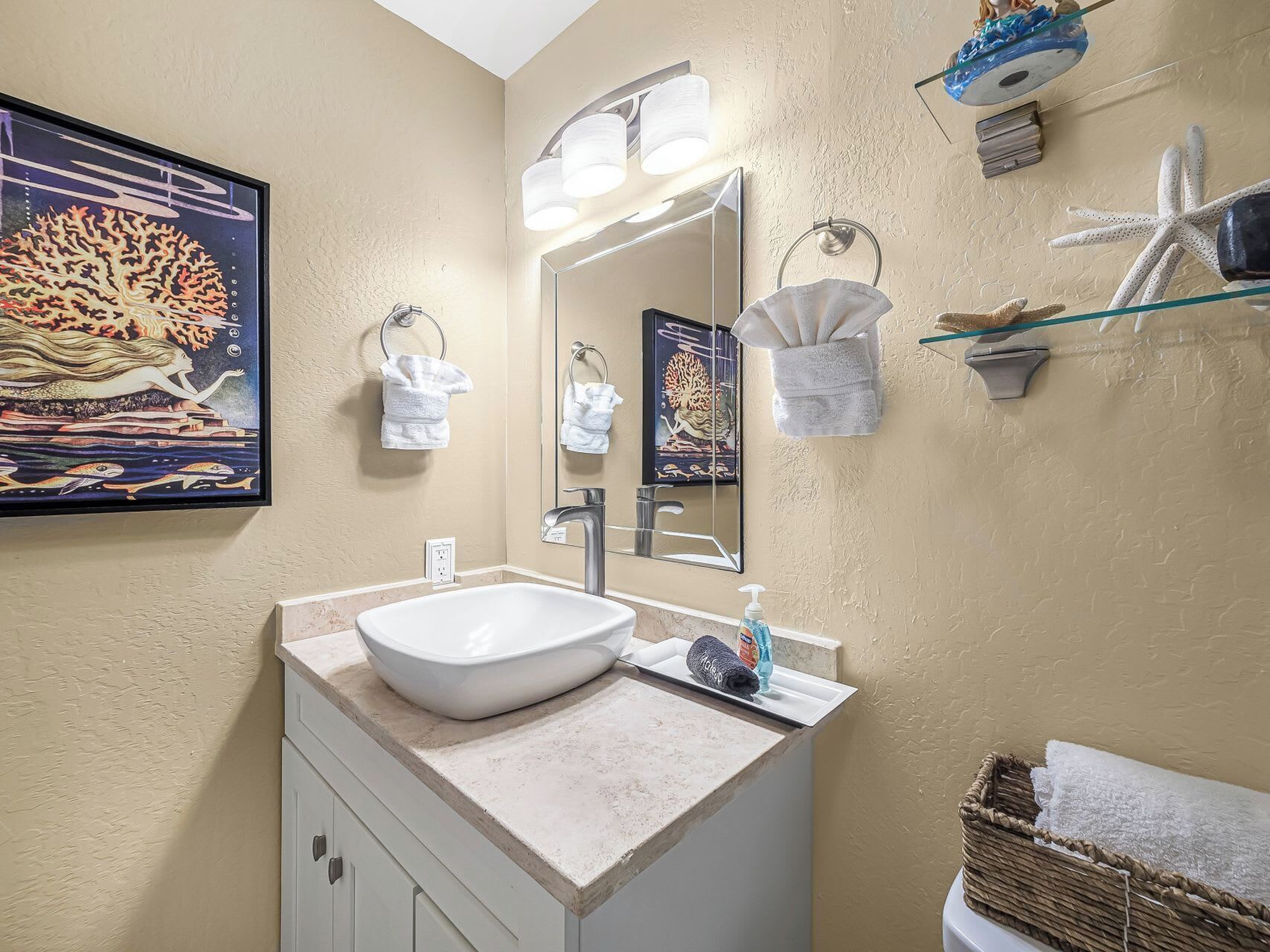 A bathroom with a large mirror, a sink, and a towel rack.