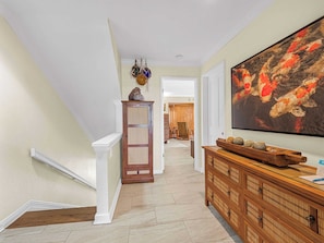 A hallway with a wooden cabinet, a painting of koi fish, and a door leading to another room. - Kick back and enjoy beautiful ocean views of Keauhou Bay from Kanaloa 3503. You'll enjoy the conveni (KAILUA-KONA)