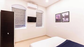 A bedroom with a bed, a TV mounted on the wall, and two framed pictures.