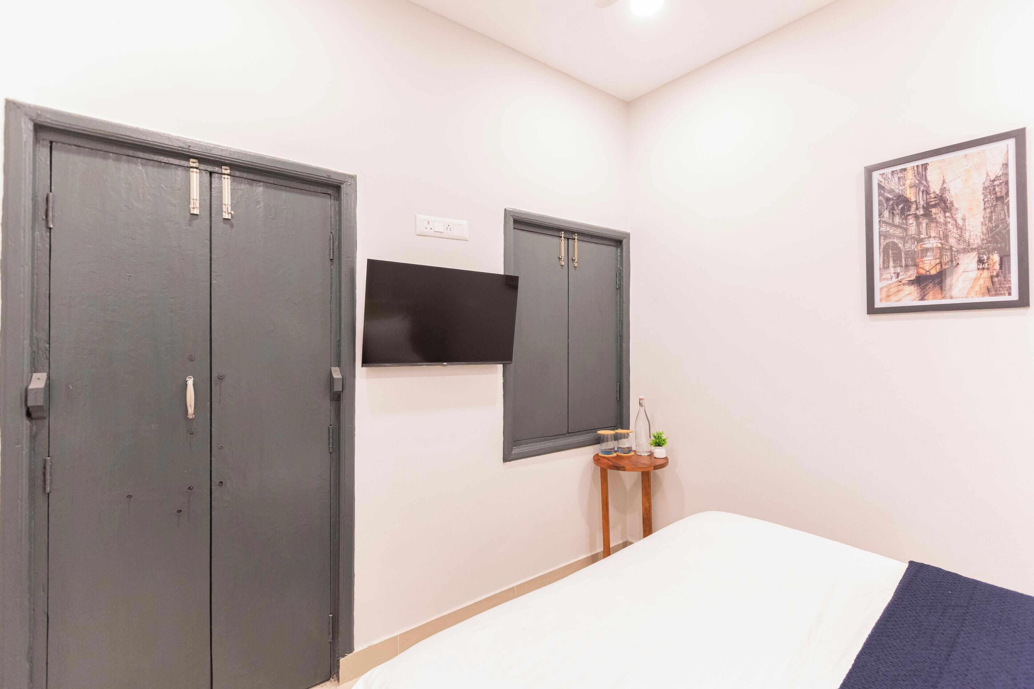 Une chambre à coucher avec un lit, une armoire, un miroir et une petite table sur laquelle est posée une plante.