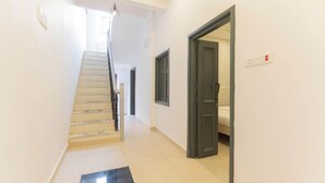 A hallway with a staircase, a door, and a light switch on the wall.