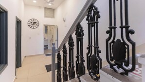 A staircase with ornate black railings, a ceiling fan, and a wall-mounted clock.