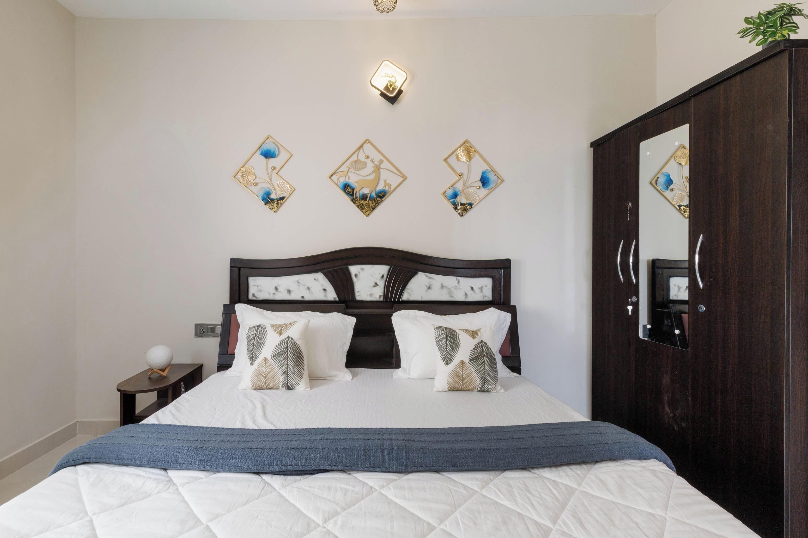 Un dormitorio con cama, mesita de noche, decoración en la pared y armario.