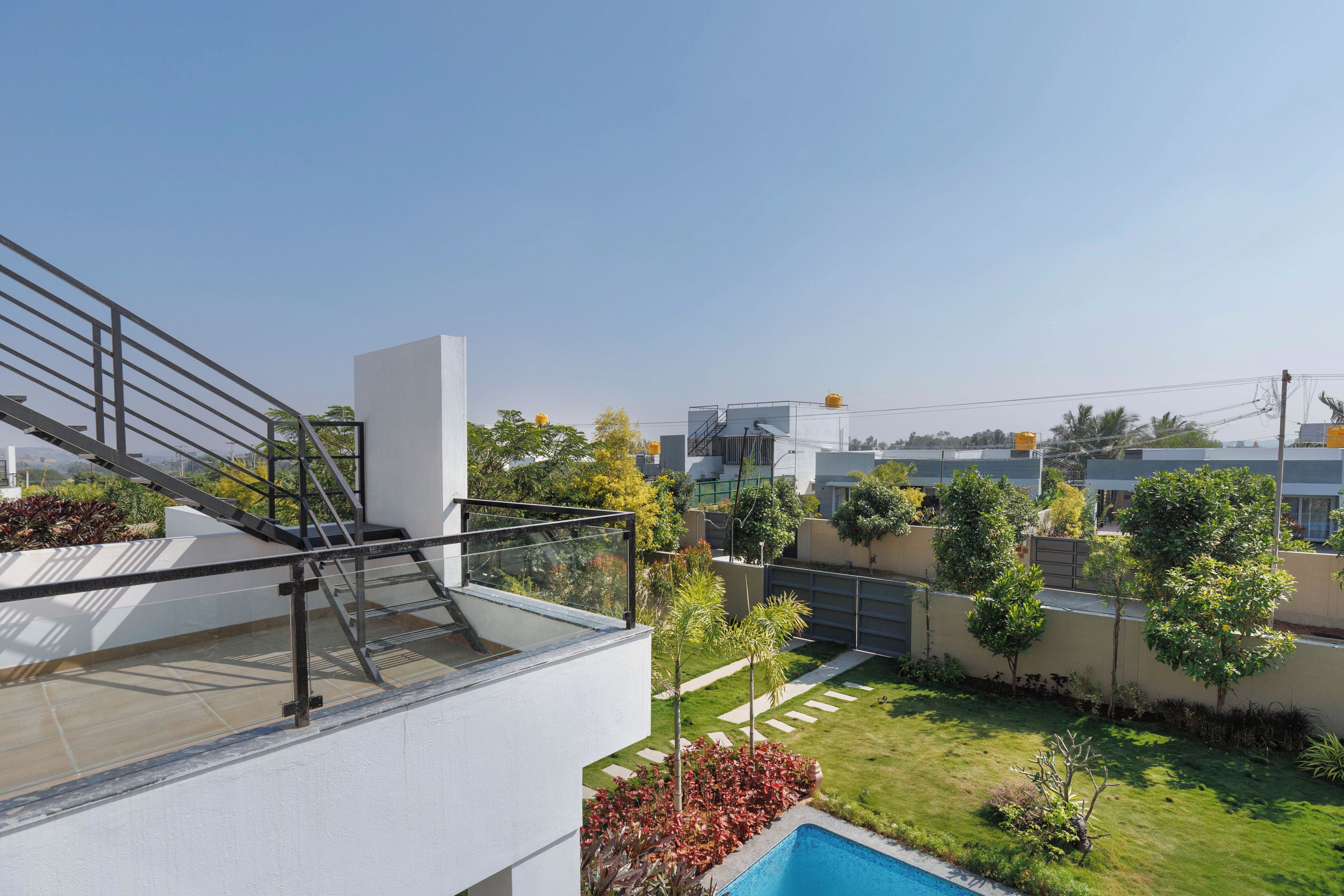 A modern residential building with a rooftop terrace, a swimming pool, and a well-maintained garden.