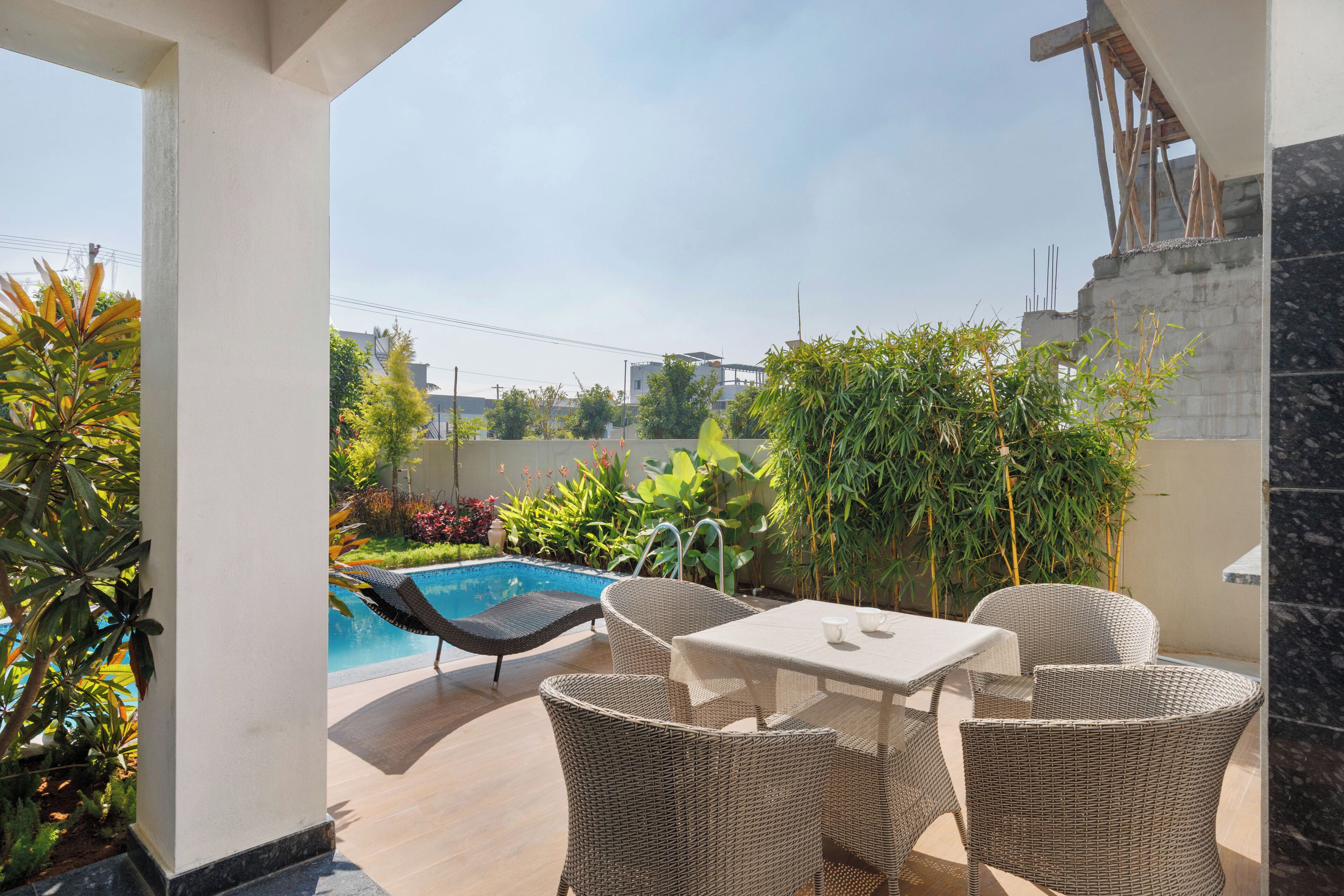 A patio area with a pool, wicker furniture, and a view of the neighborhood.