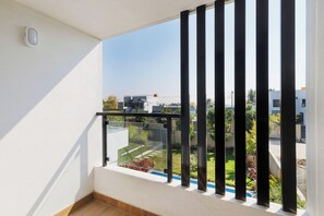 A balcony with a view of a residential area, a white wall, and a small window. - Azure Lumina by Stayjade3bhkpool Garden1hr HSR (Shoolagiri)