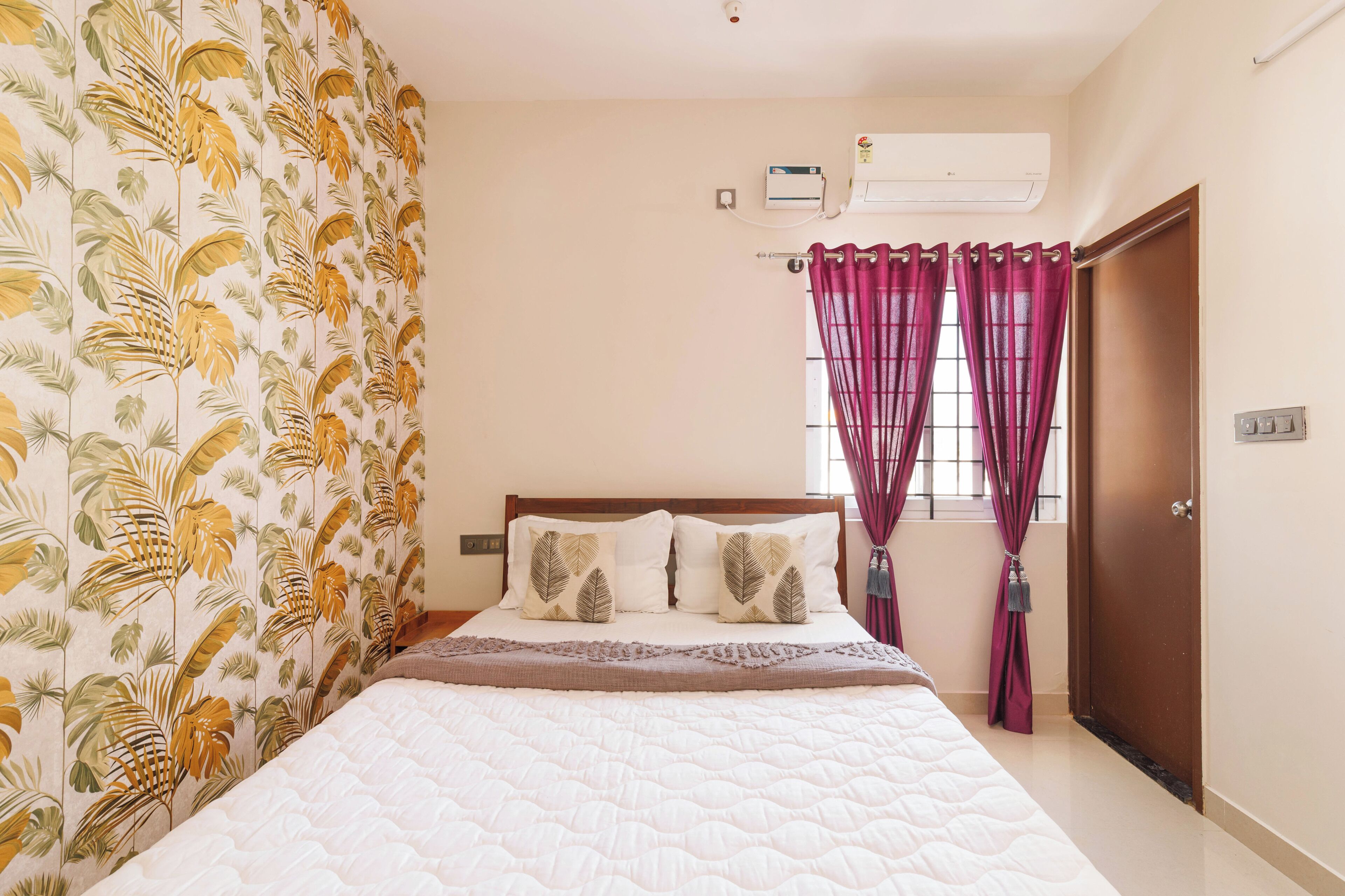 Quarto com cama, cortinas, ar-condicionado e uma porta.