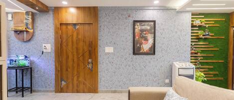 Una sala de estar moderna con puerta de madera, sofá, mesa de centro y aire acondicionado instalado en la pared.
