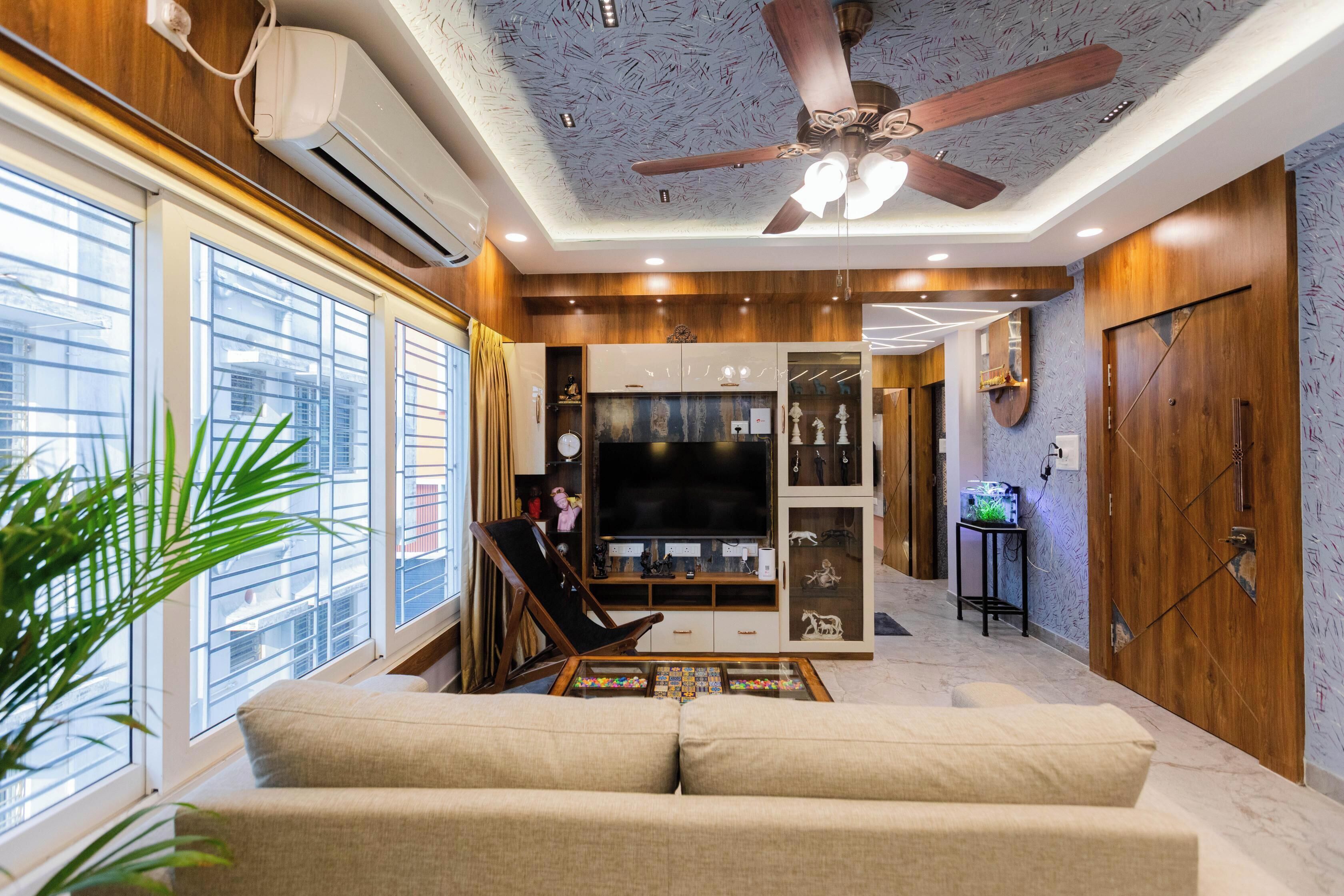 Un salon comprenant un canapé, un téléviseur, un ventilateur de plafond et une grande fenêtre.