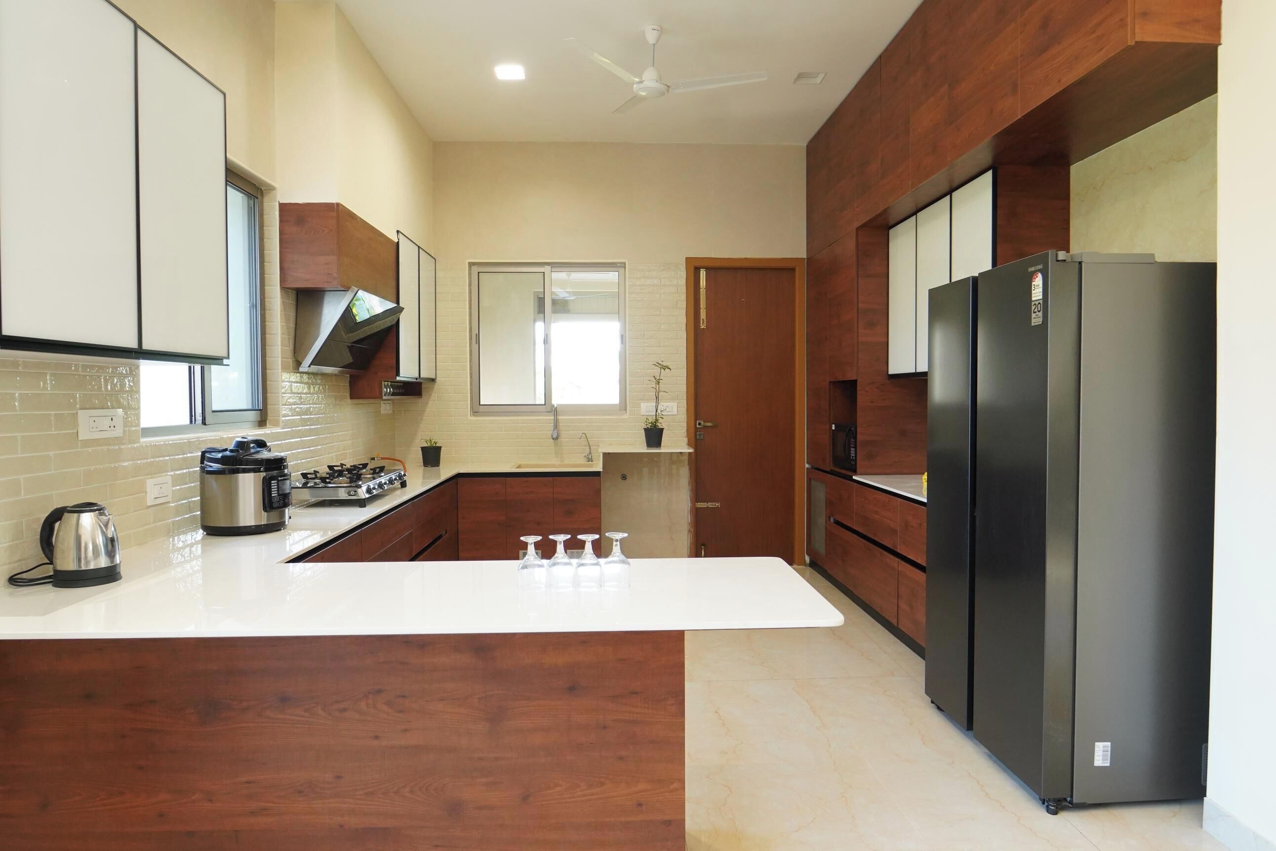 A modern kitchen with a central island, stainless steel appliances, wooden cabinetry, and a large refrigerator.