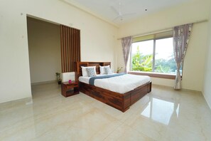 A bedroom with a large bed, a nightstand, a potted plant, and a window with curtains. - Aurora Mansion by Red Olive 3bhk Nr ECR Beach (Chennai)
