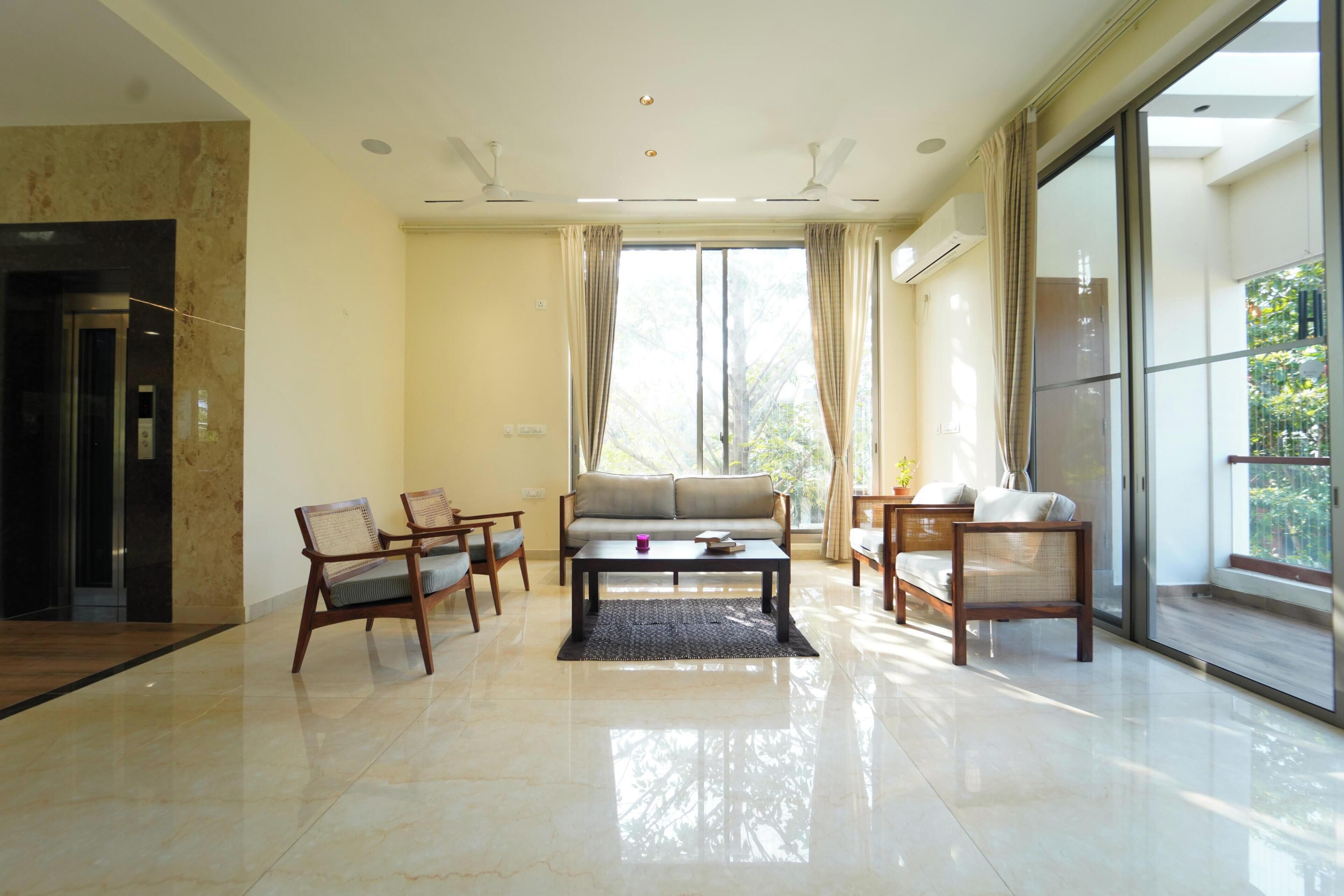 A spacious living area with a sofa, chairs, a coffee table, and a large window with curtains.