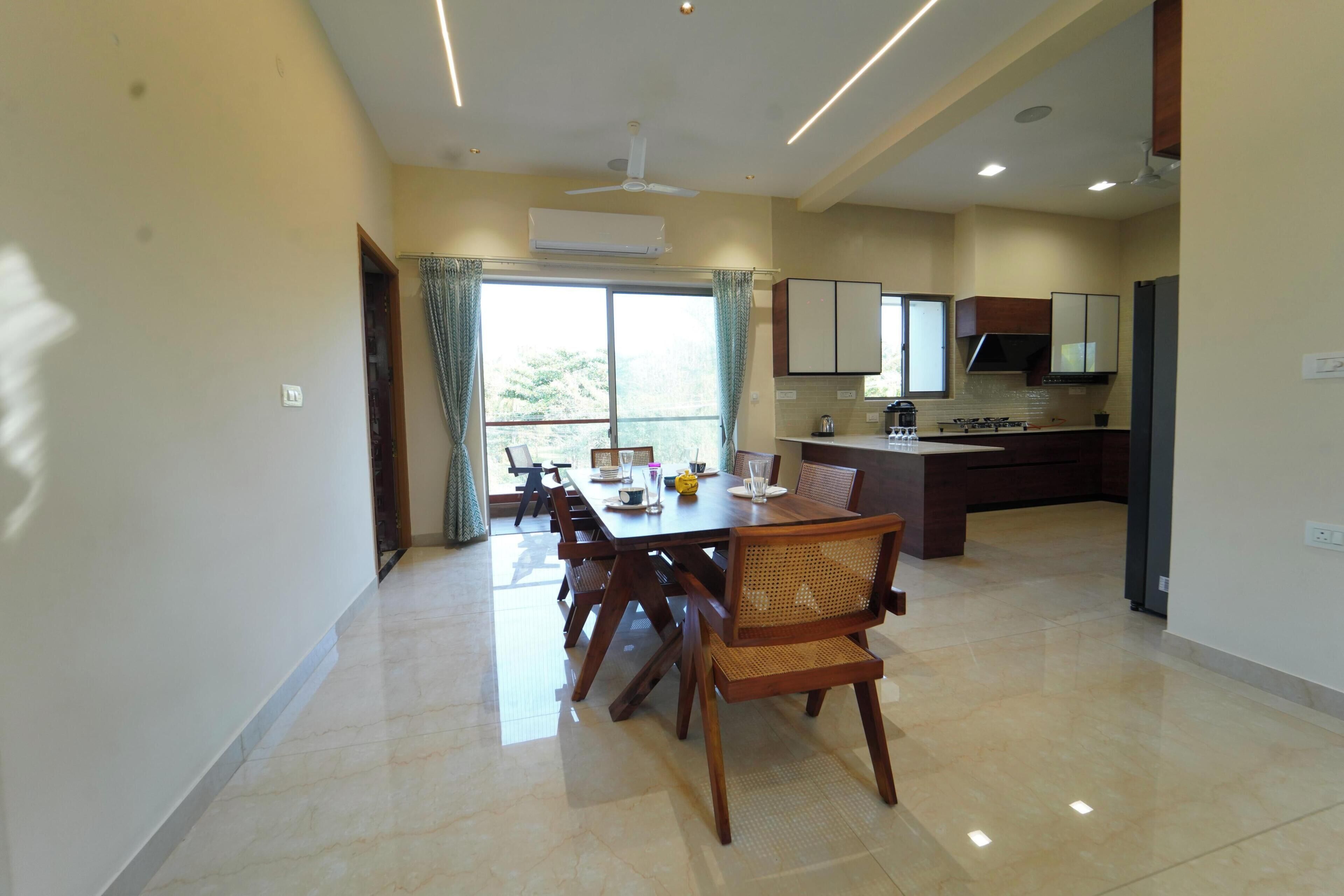 A modern kitchen with a dining area, a ceiling fan, and a large window with curtains.