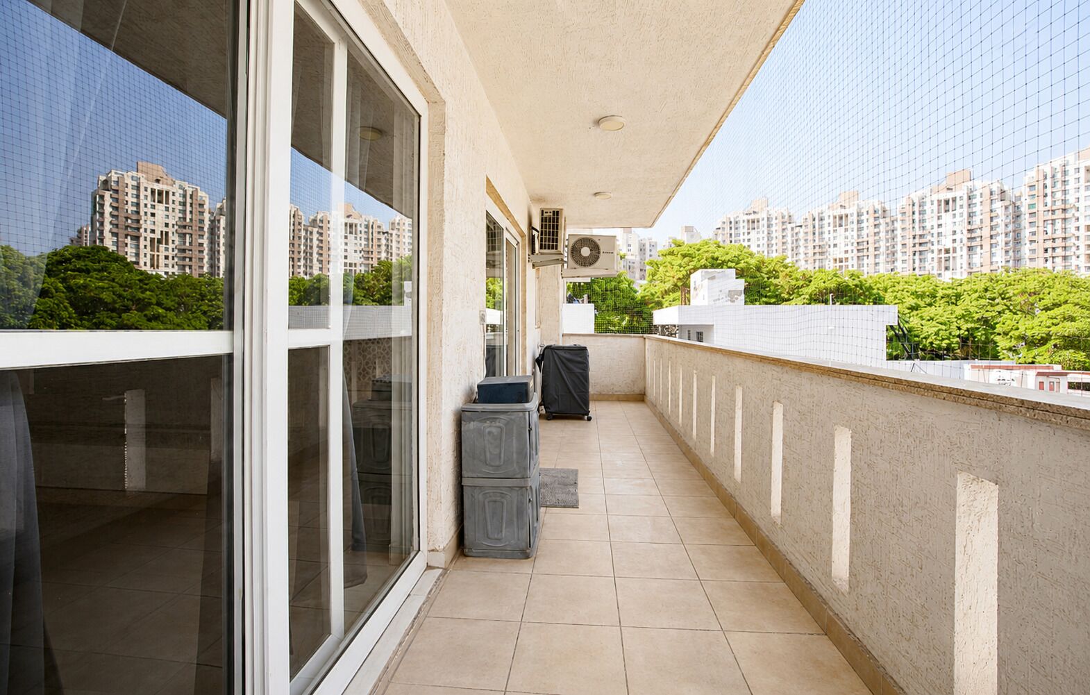 A balcony with a view of high-rise buildings, a trash bin, and a grill.