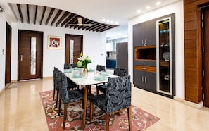 Un comedor con una mesa dispuesta para seis personas, rodeada de sillas estampadas, un jarrón decorativo y una alfombra con diseño.