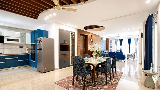 Eine moderne Küche mit blauen Schränken, einem Edelstahl-Kühlschrank und einem Essbereich mit einem Tisch für sechs Personen.
