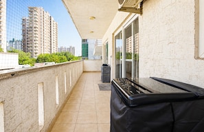 A balcony with a black grill, a trash bin, and a view of high-rise buildings. - Blossom by Redolive 3bhk Golf Course Ext (Gurugram)
