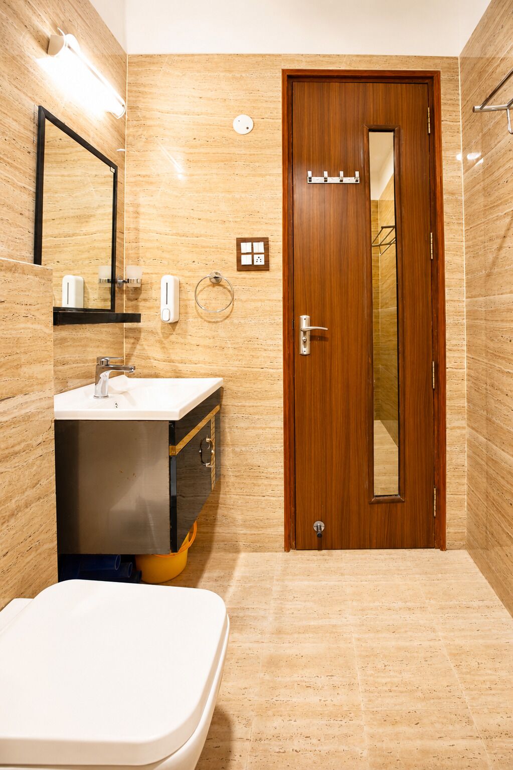 Une salle de bain avec une porte en bois, un lavabo avec un miroir et un porte-serviettes.