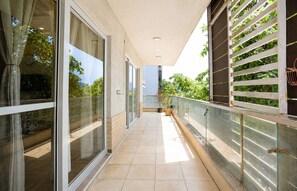 A corridor with glass doors, a tiled floor, and a metal railing. - Blossom by Redolive 3bhk Golf Course Ext (Gurugram)