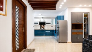 Eine moderne K üche mit blauen Schränken, einem Edelstahlkühlschrank und einer Holztür mit einem dekorativen Muster.