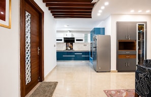 Una cocina moderna con armarios azules, un refrigerador de acero inoxidable y una puerta de madera con un diseño decorativo.