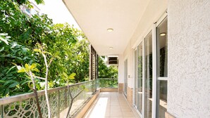 Ein überdachter Balkon mit Glastüren, Fliesenboden und Geländer.
