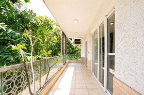 Ein überdachter Balkon mit Glastüren, Fliesenboden und Geländer.