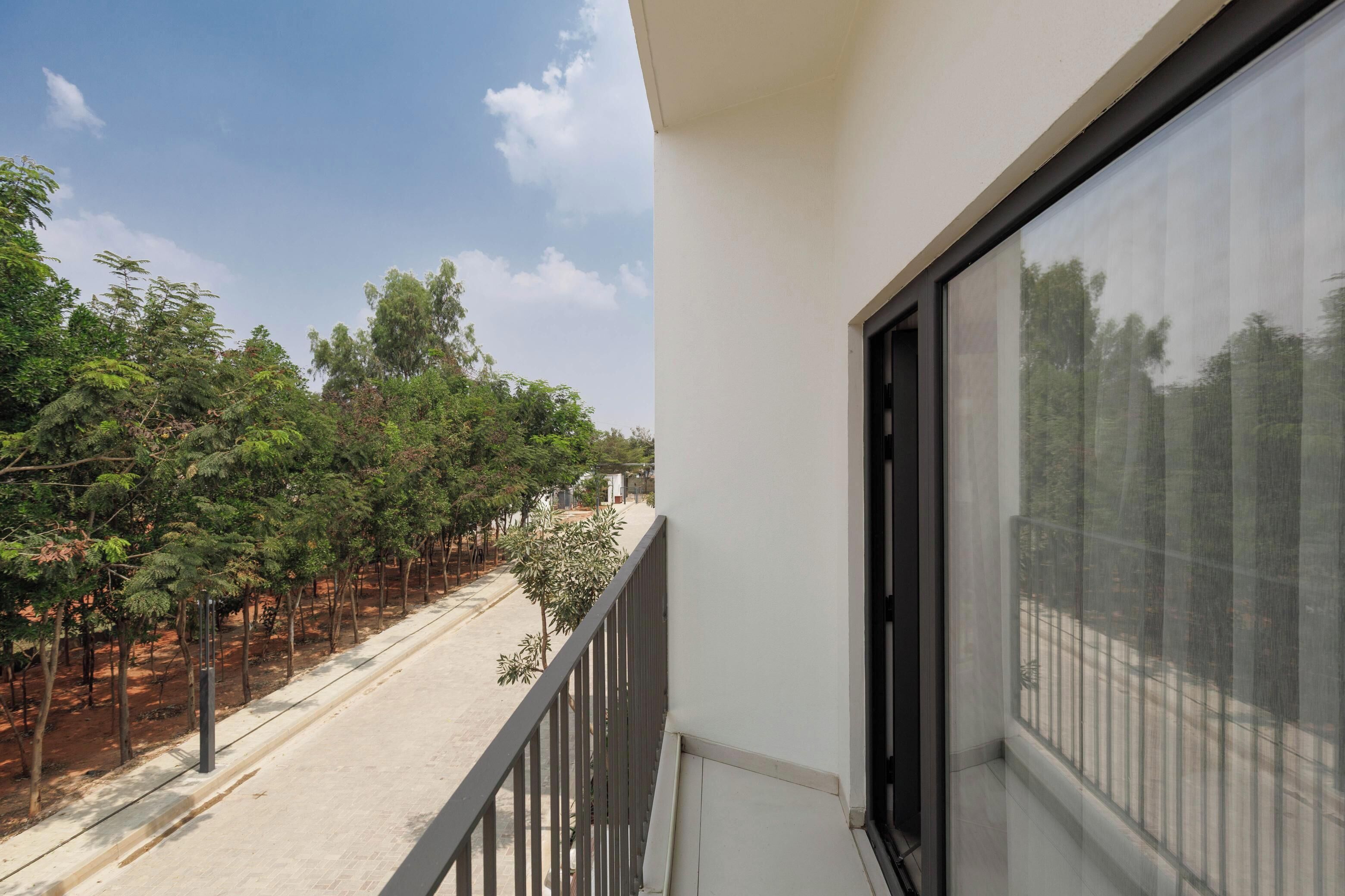 Ein Balkon mit Blick auf eine von Bäumen gesäumte Straße.