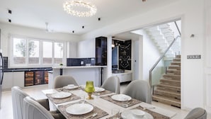 A modern kitchen with a dining area, featuring a staircase and a view of the outdoors.