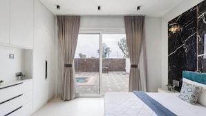 A modern bedroom with a large bed, a marble accent wall, and a view of a swimming pool and brick wall.
