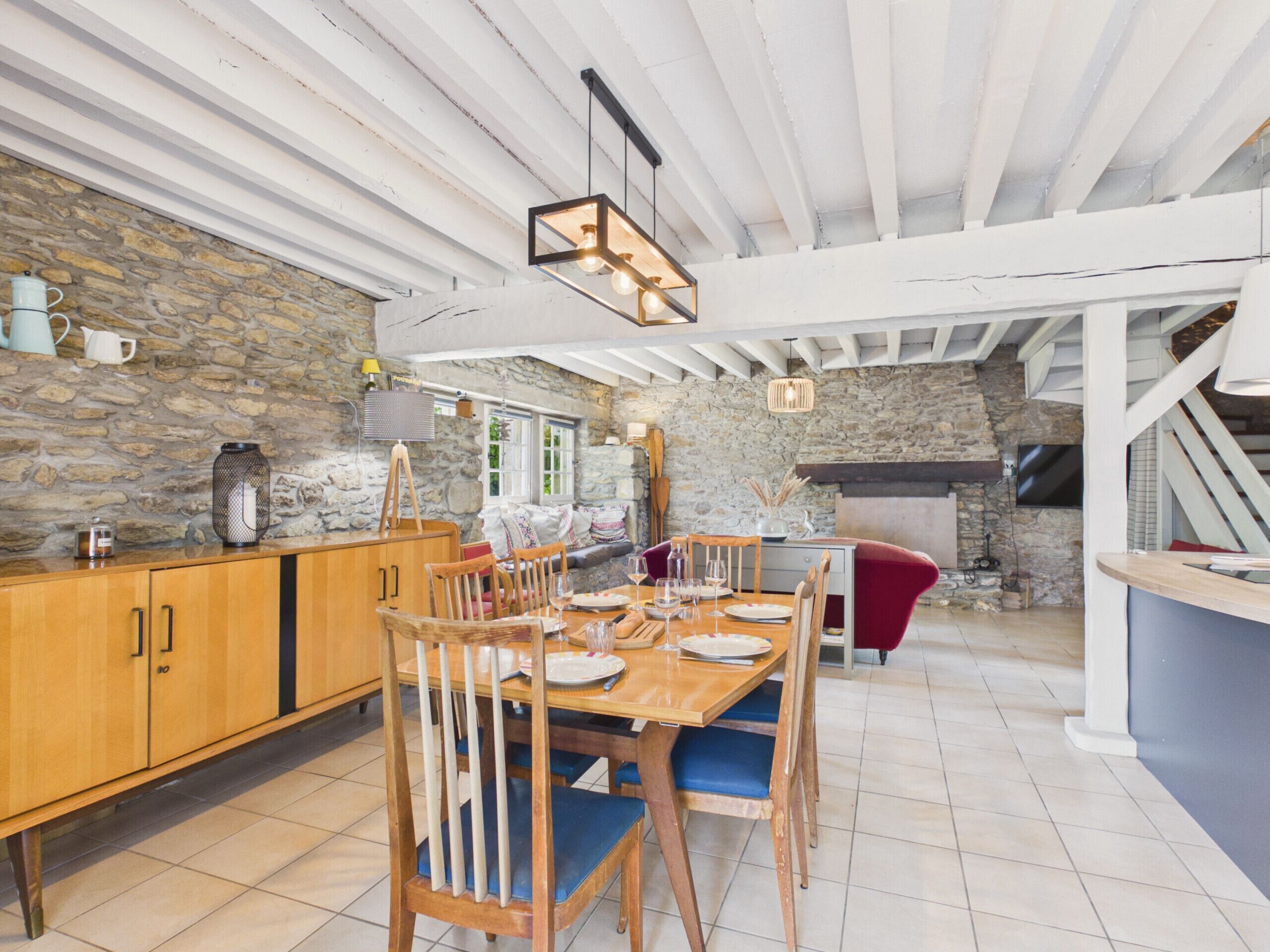 A dining area with a wooden table, chairs, and a stone wall.