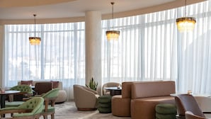 A hotel lobby with a large window, a chandelier, a sofa, and a coffee table.