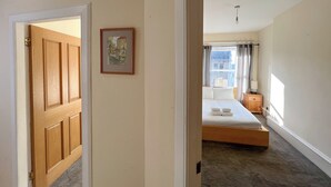 A bedroom with a bed, a nightstand, a lamp, and a window with curtains. - Charming Edinburgh Stay Near the Shore (Edinburgh)