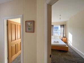 A bedroom with a bed, a nightstand, a lamp, and a window with curtains. - Charming Edinburgh Stay Near the Shore (Edinburgh)