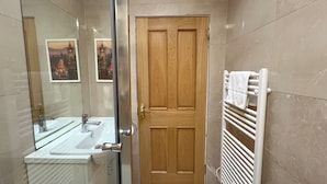 A bathroom with a wooden door, a white sink, a mirror, and a towel rack. - Charming Edinburgh Stay Near the Shore (Edinburgh)