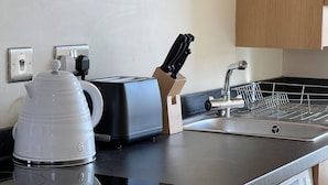 A kitchen with a coffee maker, toaster, knife block, and a sink. - Charming Edinburgh Stay Near the Shore (Edinburgh)
