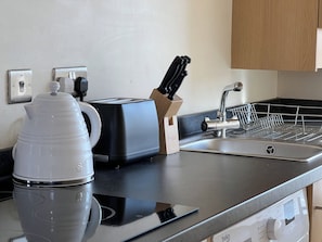 A kitchen with a coffee maker, toaster, knife block, and a sink. - Charming Edinburgh Stay Near the Shore (Edinburgh)