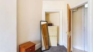 A hallway with a wooden dresser, a mirror leaning against the wall, and a door leading to another room. - Charming Edinburgh Stay Near the Shore (Edinburgh)