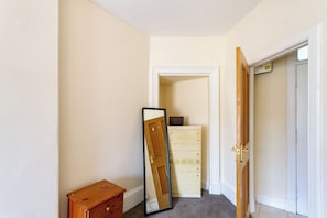 A hallway with a wooden dresser, a mirror leaning against the wall, and a door leading to another room. - Charming Edinburgh Stay Near the Shore (Edinburgh)