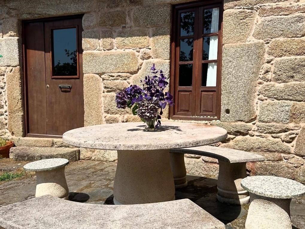 Un bâtiment en pierre avec une table ronde et des bancs, une porte et une fenêtre.