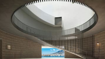 Un interior moderno con una escalera de caracol, vista al puerto y una pared de ladrillo.