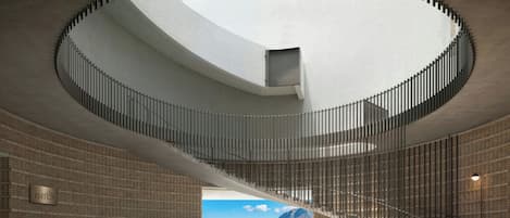 Un interno moderno con una scala a chiocciola, vista su un porto e una parete in mattoni.