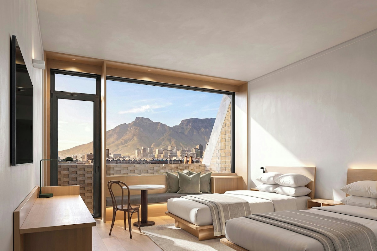 A modern bedroom with a large window, a bed, a bedside table, and a chair.
