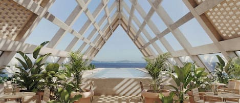 A dining area with a view of the sea, featuring terracotta planters and wooden furniture.