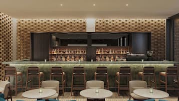 A bar area with a brick wall, multiple seating tables, and a variety of bottles on shelves.