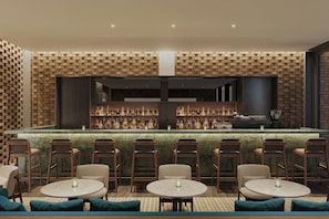A bar area with a brick wall, multiple seating tables, and a variety of bottles on shelves. - The Cape Town EDITION (CAPE TOWN)