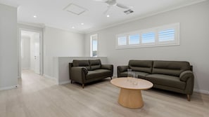 Un salon moderne avec deux canapés, une table basse et un ventilateur de plafond.