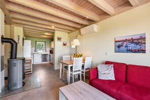 A compact living space with a kitchen, dining area, and a red sofa. - Apartment 'Ferienhaus Meerblick' with Sea View, Wi-Fi, and Air Conditioning (Sierksdorf)